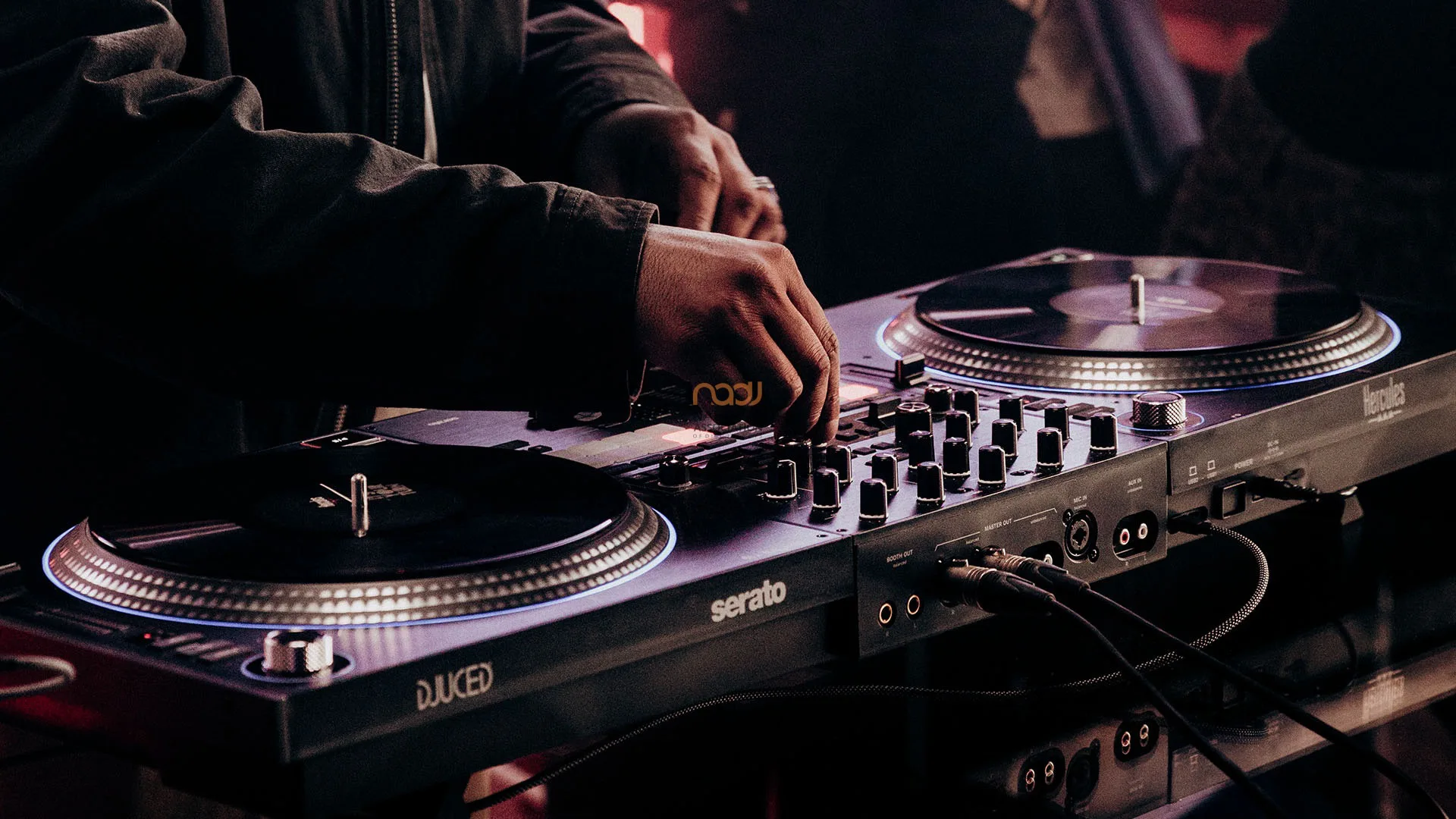 DJ mexendo nos botões do mixer da Hercules DJControl T10, com os dois pratos motorizados iluminados