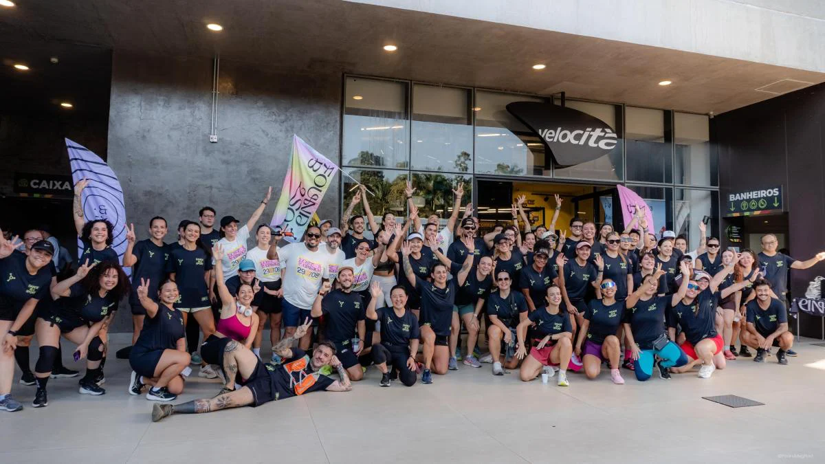 Grupo de corredores reunido num treino de aquecimento do Lost & Found, com a bandeira do festival erguida no meio