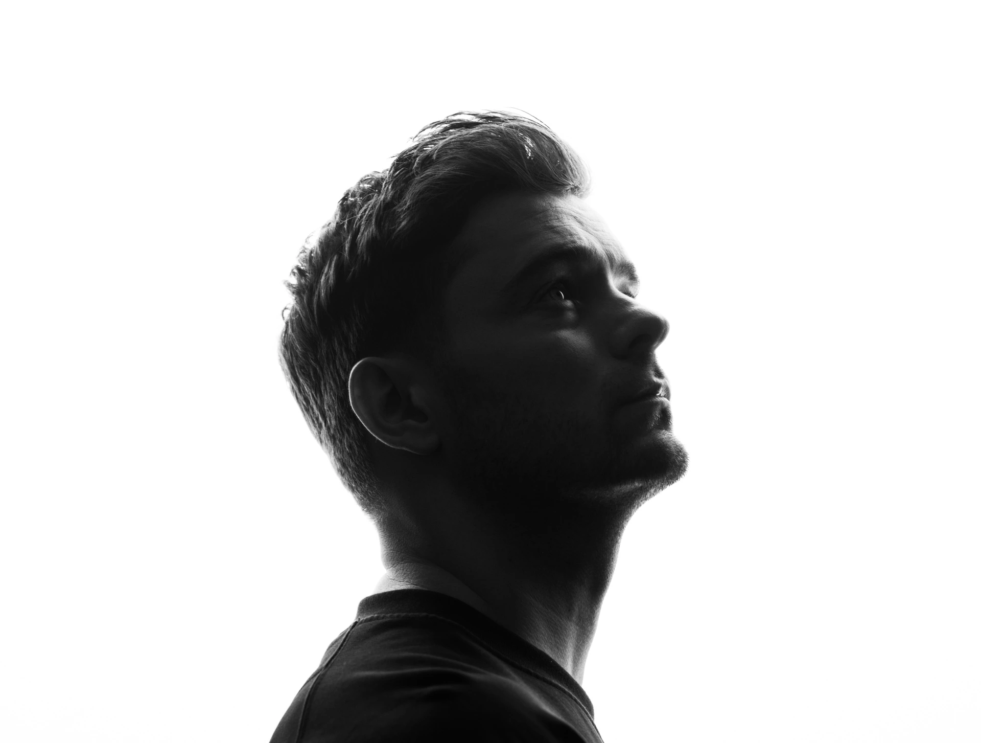 Retrato em preto e branco de Martin Garrix de perfil, olhando para cima, em silhueta contra fundo branco