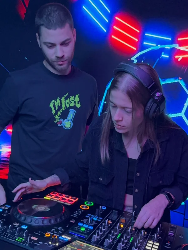 Aluna DJ com fones tocando no Pioneer DJ com iluminação neon · DJ Ban EMC